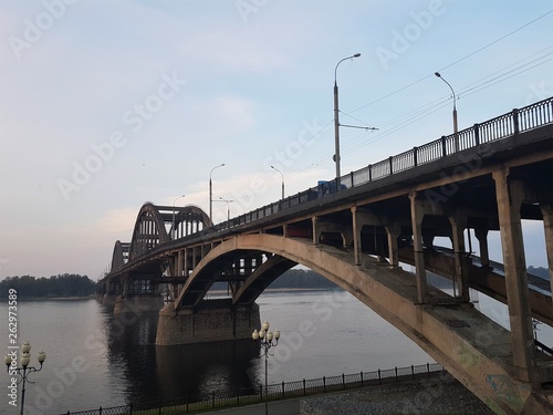 Volga bridge and embankment over Volga river at sunset, Yaroslavl region, Rybinsk city, Russia. Beautiful landscape with water © Konstantin