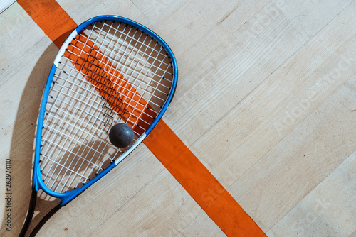 Top view of squash racket and ball on wooden surface photo