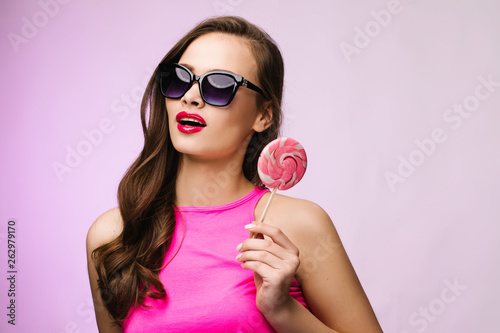 Glamorous girl wearing sunglasses holding pink lollipop