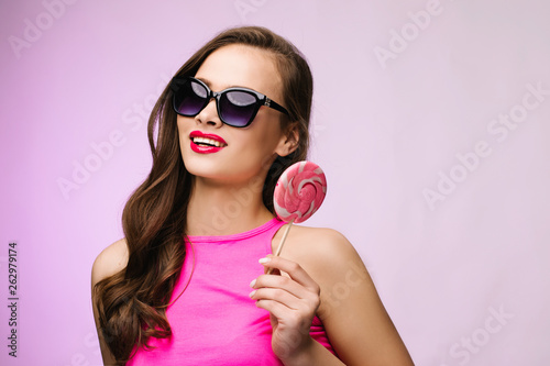 Glamorous girl wearing sunglasses holding pink lollipop