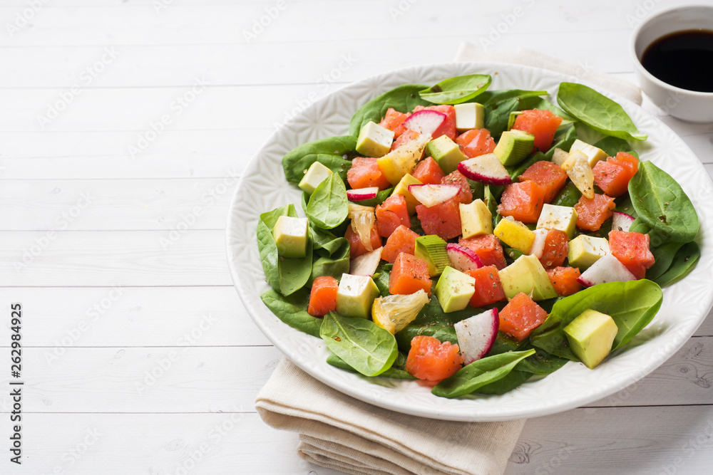 Poke Hawaiian salad with salmon, avocado spinach and vegetables in a plate on a white table. Poke Hawaiian salad with salmon, avocado spinach and vegetables in a plate on a white table.