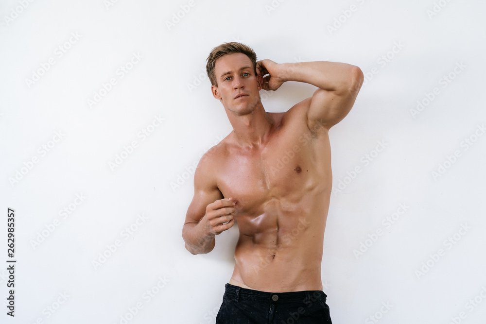 Fototapeta premium Sexy athletic man with naked torso on white background. Fashion portrait of sporty healthy guy