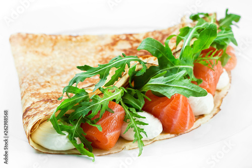 Pancake with salmon fish cheese and arugula on white background