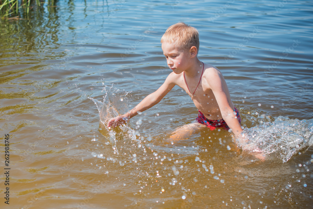 Boy playing on the beach on summer holidays. Children in nature with beautiful sea, sand and blue sky. Happy kids on vacations at seaside in the water Boy playing on the beach on summer holidays. Children in nature with beautiful sea, sand and blue sky. Happy kids on vacations at seaside in the water