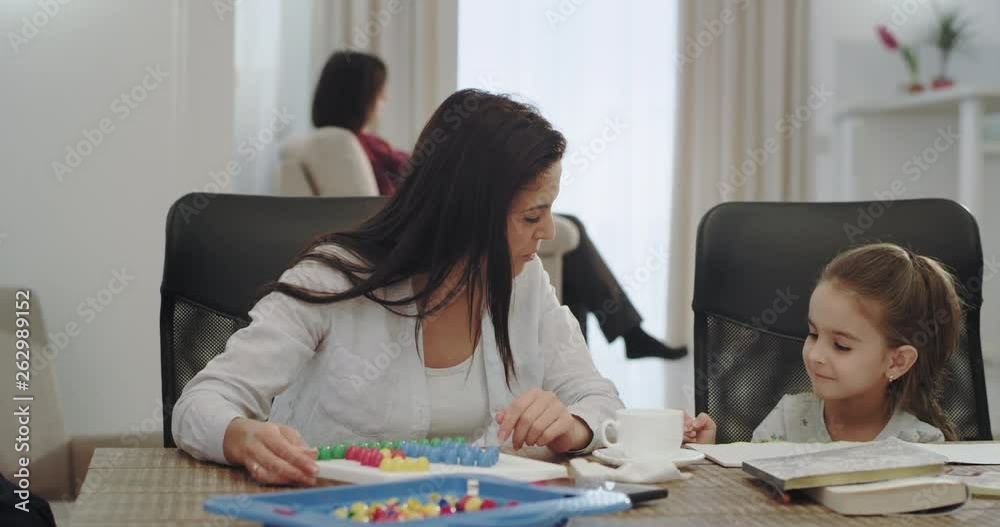 Perfect morning on the weekend mature mother have a great time with her kids , playing table game with a small girl and other two kids playing on smartphone, background old granny reading a book. 4k Perfect morning on the weekend mature mother have a great time with her kids , playing table game with a small girl and other two kids playing on smartphone, background old granny reading a book. 4k