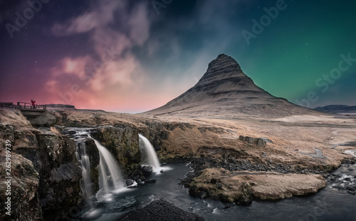 Northern lights aurora borealis over Kirkjufell mountain and waterfall in Iceland © Tharanga