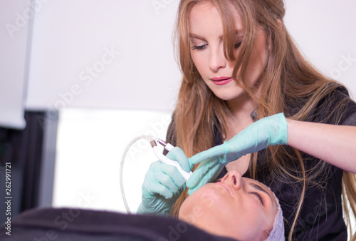 Portrait of young attractive beautician applying facial treatment.