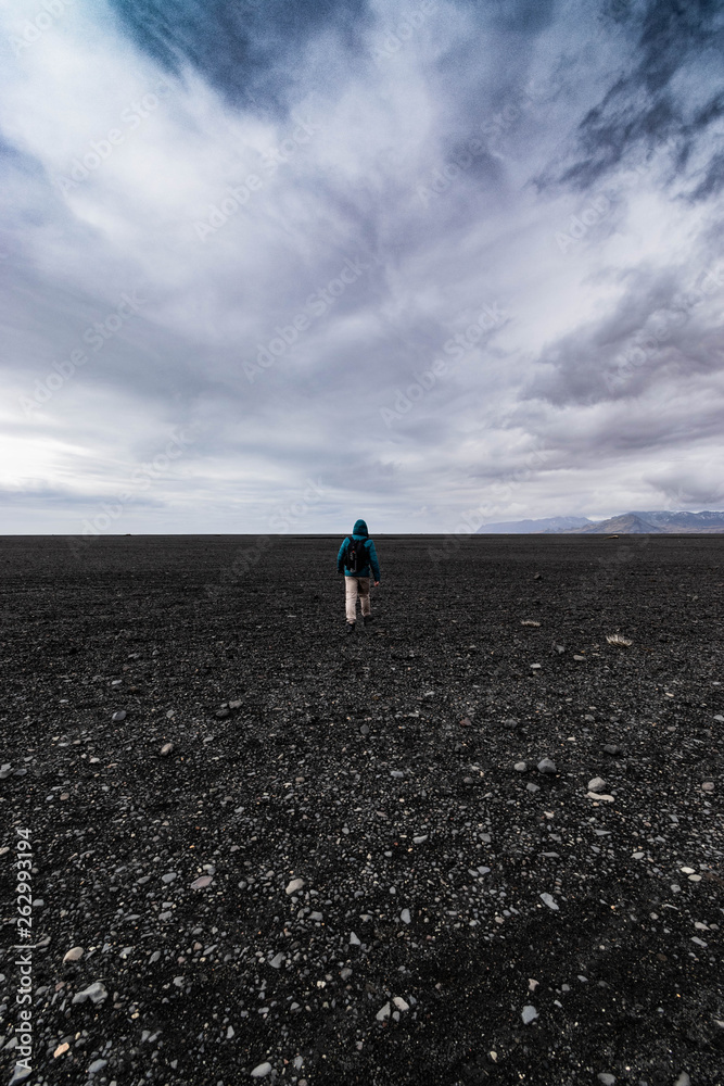 Fototapeta premium man walking on the black beach