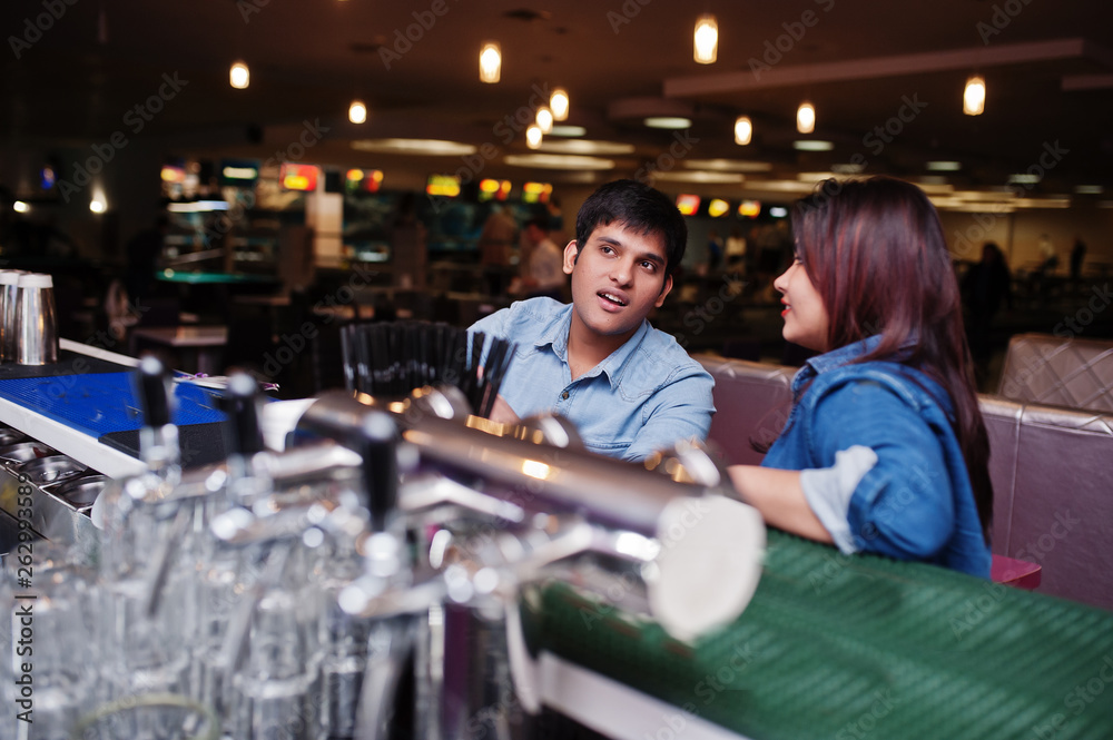 Stylish asian couple wear on jeans sitting on chair at bar in club.