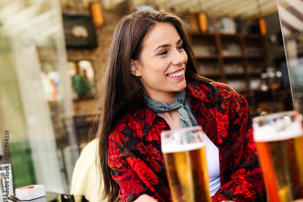 Girl having a beer while waiting for a friend. Long haired woman drinking beer at a bar. Girl in a flannel shirt at a bar. 