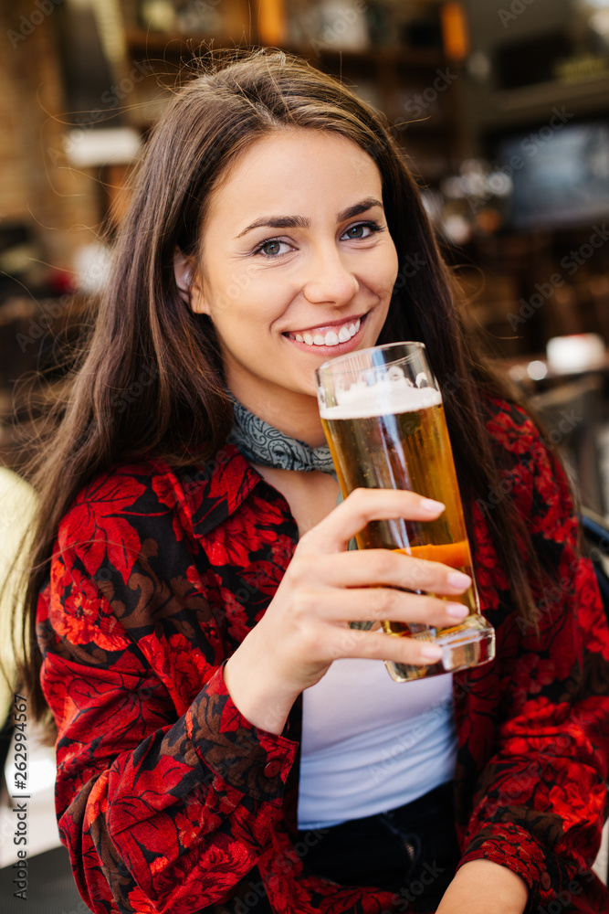 Girl having a beer while waiting for a friend. Long haired woman