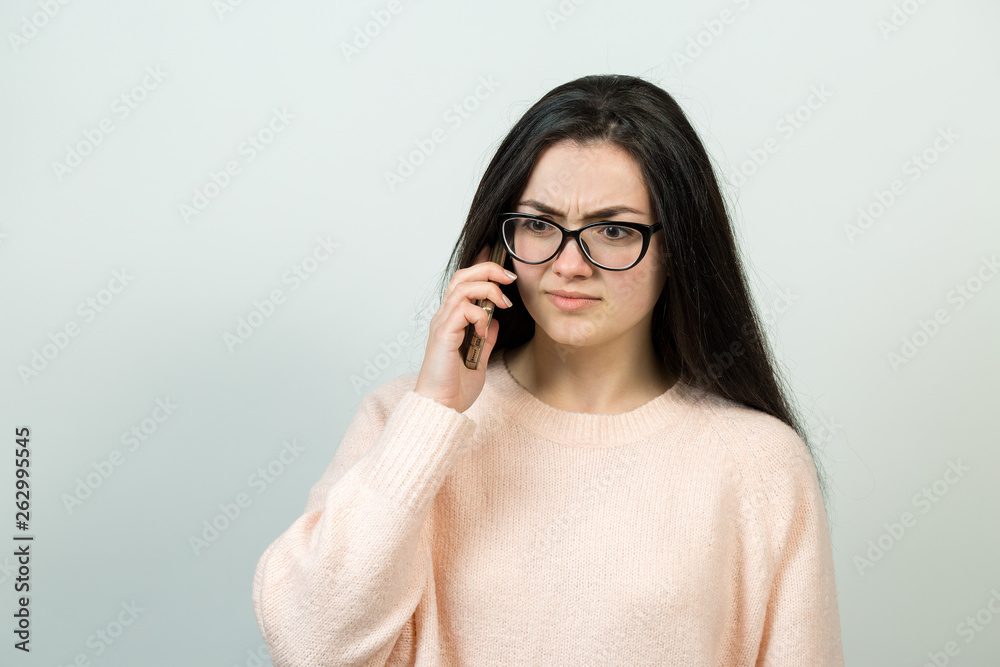 Young beautiful woman using mobile phone studio on white color background. Looking attentively at screen of cellphone, browsing web pages.