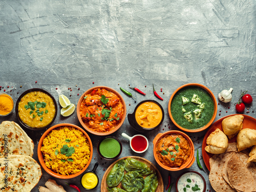 Indian cuisine dishes: tikka masala, dal, paneer, samosa, chapati, chutney, spices. Indian food on gray background. Assortment indian meal with copy space for text. Top view or flat lay.