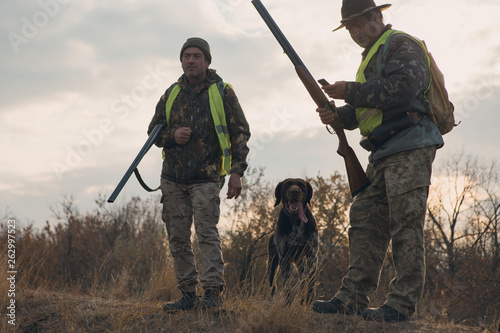 Hunters with a german drathaar and spaniel, pigeon hunting with dogs in reflective vests 