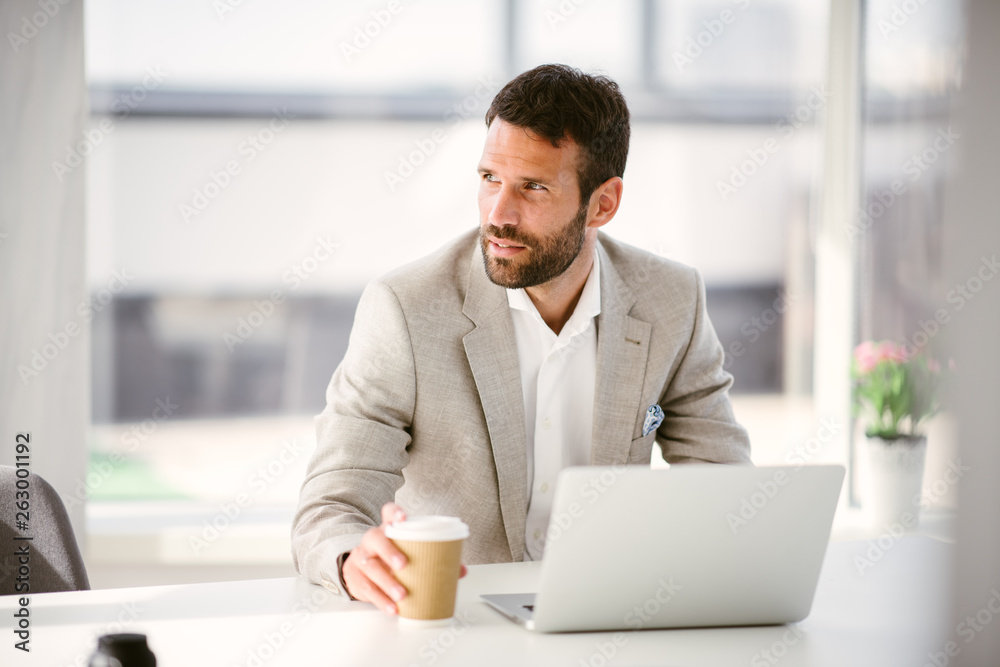 Manager drinking coffee while working on laptop. Businessman sips coffee while he works. Manager drinking coffee while working on laptop. Businessman sips coffee while he works.