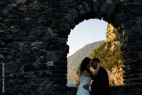 Beautiful romantic wedding couple posing in old window with view at sea