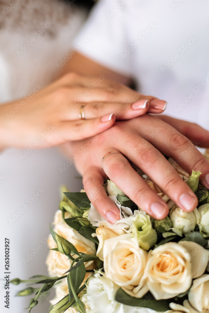 newlyweds demonstrate wedding rings over a bouquet of roses newlyweds demonstrate wedding rings over a bouquet of roses