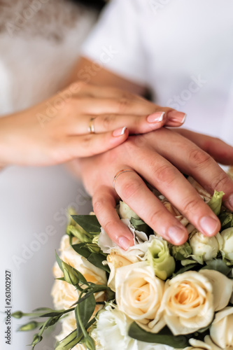 newlyweds demonstrate wedding rings over a bouquet of roses