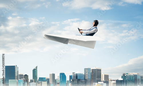 Aviator driving paper plane above business center