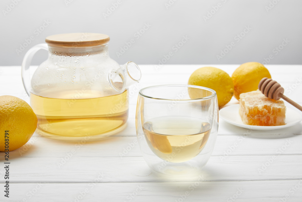 teapot with organic herbal tea, glass, fresh lemons and honeycomb on white wooden table teapot with organic herbal tea, glass, fresh lemons and honeycomb on white wooden table