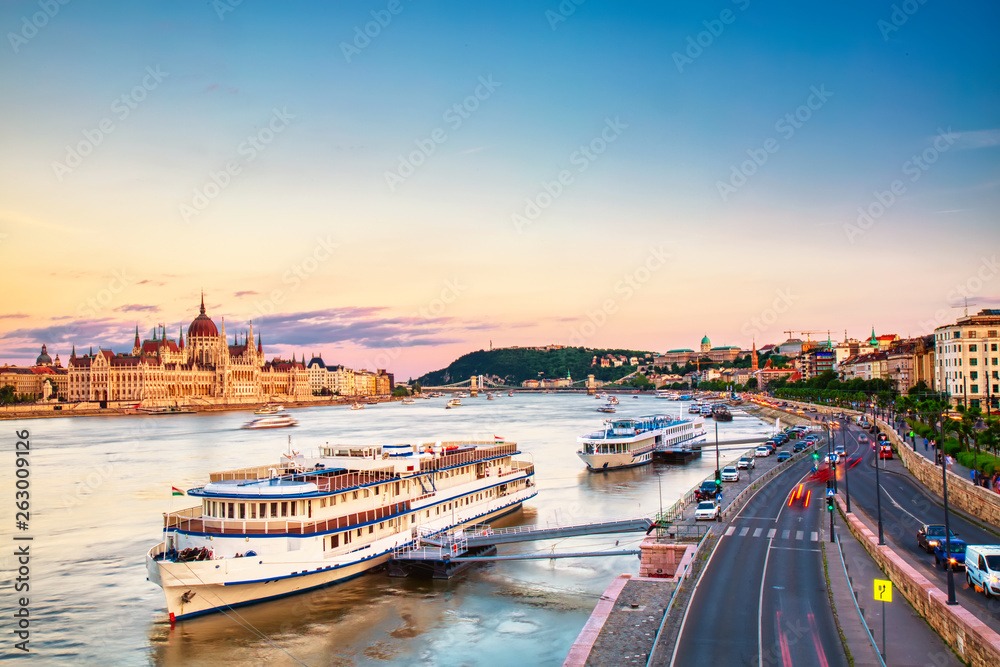 Travel and european tourism concept. Parliament and riverside in Budapest Hungary with sightseeing ships during amazing sunset. Parliament and Danube river in Hungary.