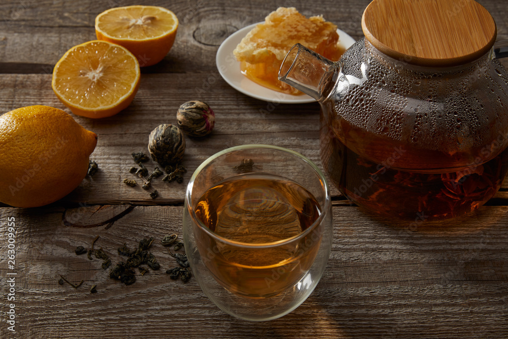 lemons, honeycomb and transparent teapot with glass of chinese blooming tea on wooden surface lemons, honeycomb and transparent teapot with glass of chinese blooming tea on wooden surface