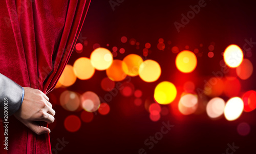 Bokeh lights behind drapery curtain and hand opening it