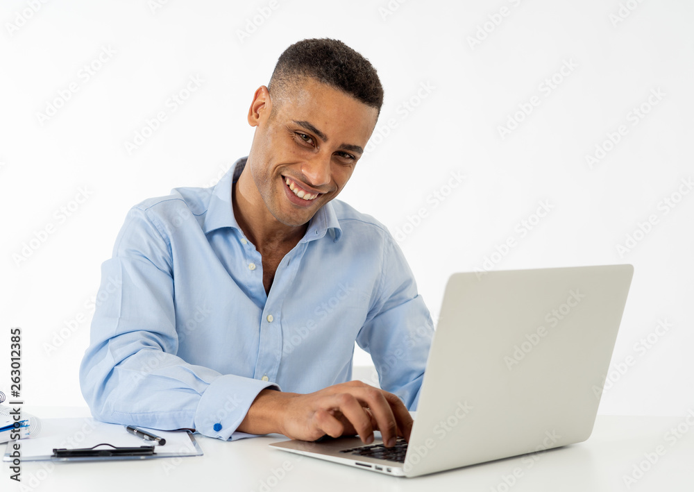 Attractive happy handsome african american businessman working on laptop computer on desk at office Attractive happy handsome african american businessman working on laptop computer on desk at office