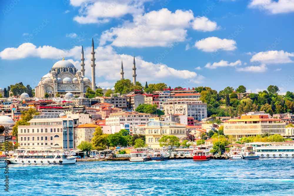 Obraz premium Touristic sightseeing ships in Golden Horn bay of Istanbul and view on Suleymaniye mosque with Sultanahmet district against blue sky and clouds. Istanbul, Turkey during sunny summer day.