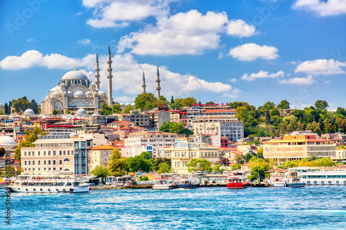 Touristic sightseeing ships in Golden Horn bay of Istanbul and view on Suleymaniye mosque with Sultanahmet district against blue sky and clouds Fototapet