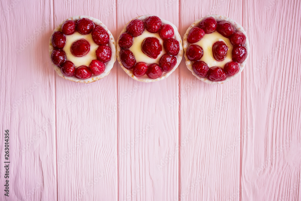 some appetizing beautiful bright panna cotta cakes in baskets with berries on a pink wooden background from the top of the frame and a large space for text below