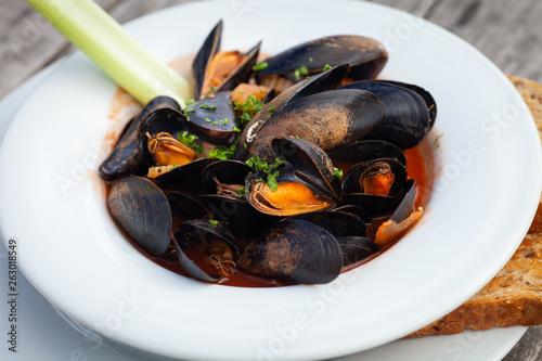 Freshly cooked mussels in a tomato and herb sauce served in a white bowl