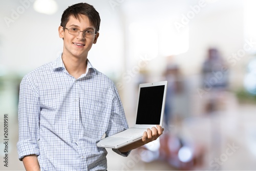 Smiling African Student man with laptop, mall background, bokeh