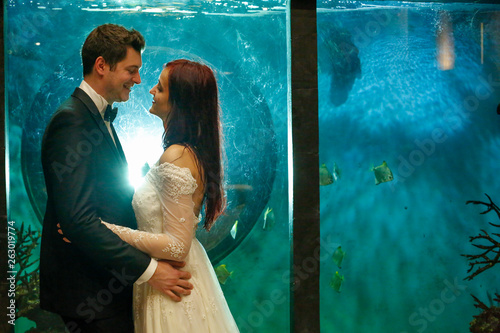 Happy wedding couple posing in front of aquarium