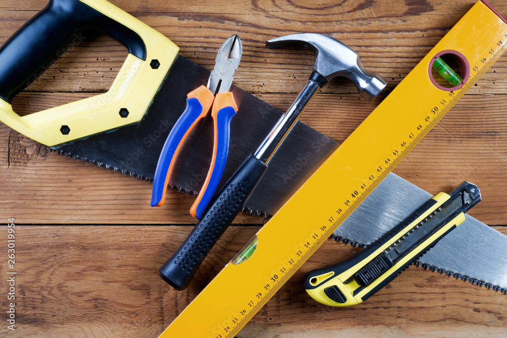Handsaw, hammer, level, model knife and pliers on wooden background Handsaw, hammer, level, model knife and pliers on wooden background
