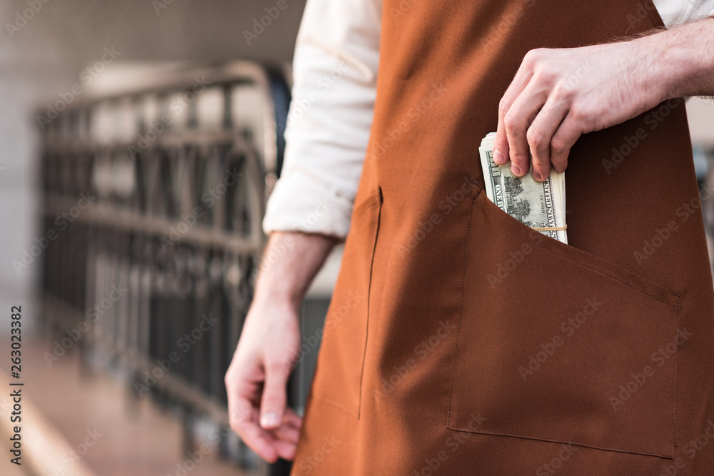 Φωτογραφία Partial view of barista in brown apron putting money in pocket