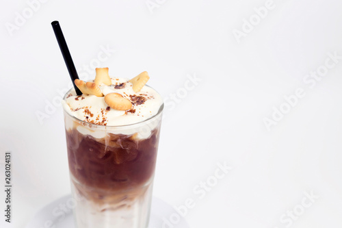Glass of cold coffee drink with whipped cream, syrup and cookies on white background. Beverages, menu concept. Close-up, copy space, layout design