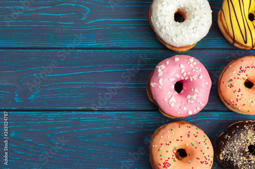 Colorful fresh donuts on dark blue wooden surface