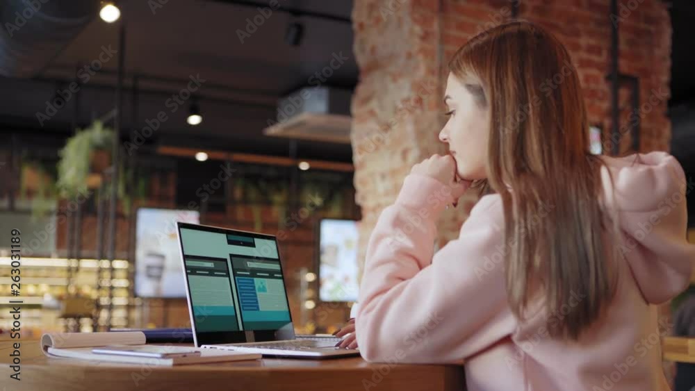 Tilt down side view of freelance female website designer creating design templates for different devices on laptop sitting at table in cafe (ATTN templates designed by ME)