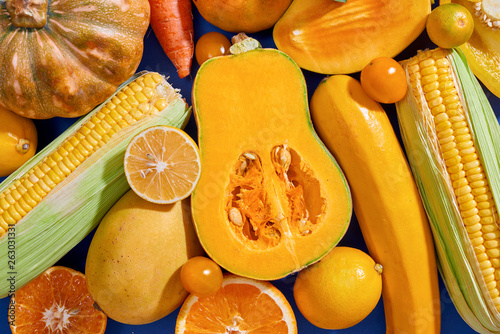 Collection of fresh yellow fruit and vegetables on the blue background