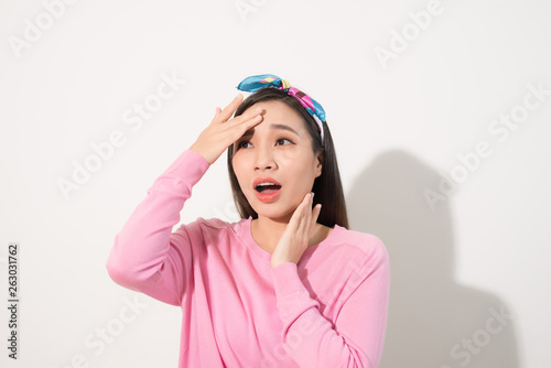 Portrait of a beautiful Asian girl covering face by hand of bright sun light. Woman in a pink dress protecting her face from solar light. Skin care or beauty concept
