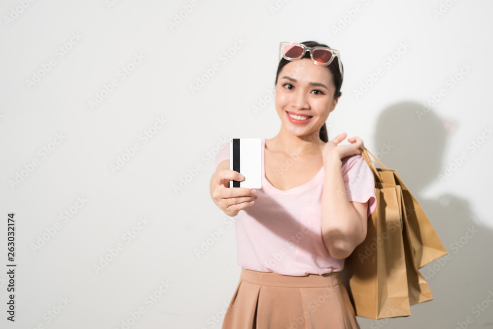 Image of cheerful young woman standing isolated over white background holding shopping bags and credit card. Looking camera. Image of cheerful young woman standing isolated over white background holding shopping bags and credit card. Looking camera.