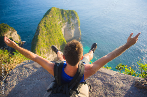 lifestyle outdoors portrait of young happy and excited man with backpack trekking beach cliff looking at beautiful sea landscape in sport adventure and summer holidays