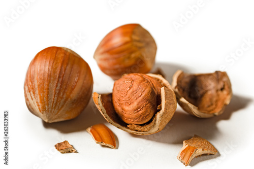 Some shelled hazelnuts with shell fragments around them, isolated on a white background