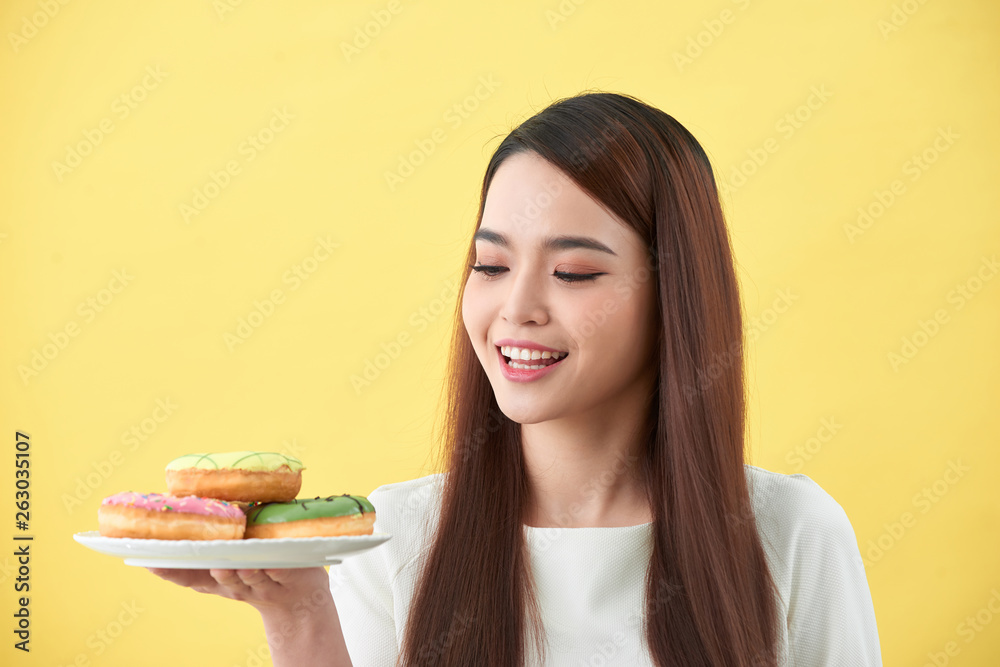 Beautiful young woman smiling holding a plate full of delicious color donuts Beautiful young woman smiling holding a plate full of delicious color donuts