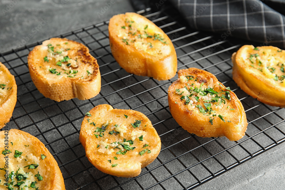 Baking rack with tasty homemade garlic bread on table, closeup Baking rack with tasty homemade garlic bread on table, closeup