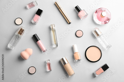 Flat lay composition with bottles of perfume and cosmetics on grey background
