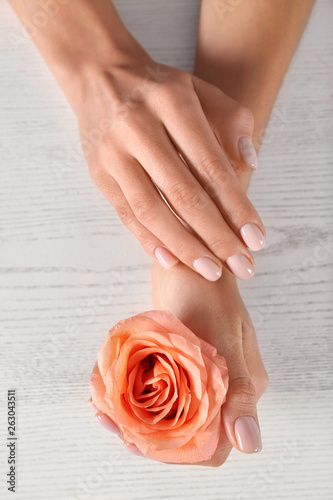 Closeup view of woman with rose at white wooden table. Spa treatment