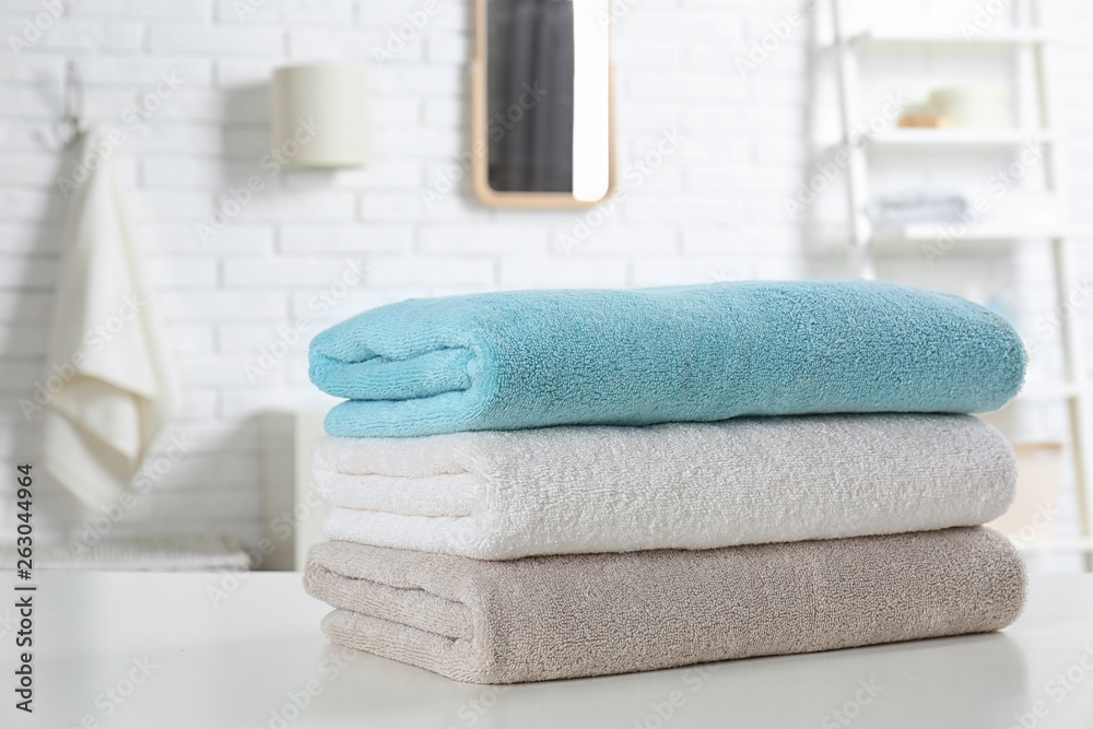 Stack of fresh towels on table in bathroom, closeup