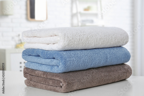 Stack of fresh towels on table in bathroom, closeup